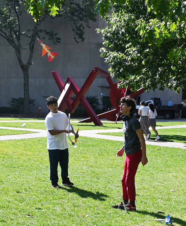 Two students outside launching a paper rocket