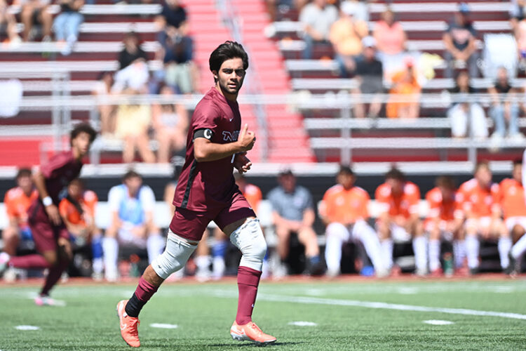 Dilin Meloni running on a soccer field with a crowd in the background.