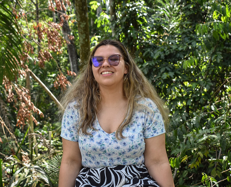 Hana sitting next to green plants in Brazil.