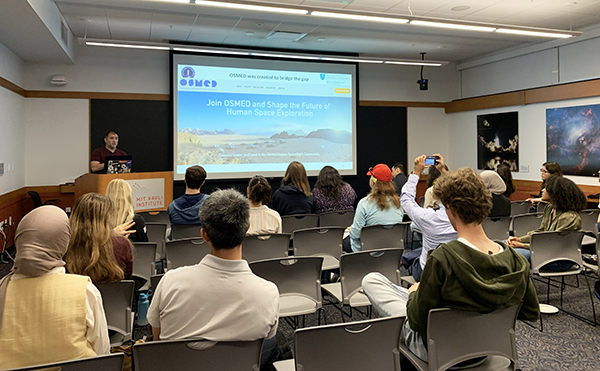 Group of students in a classroom listening to a speaker talk about space medicine.